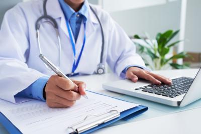 Sundhedstjek: Læge udfylder formular og skriver på computer