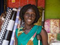 Kvindelig skrædder står foran sin butik i Uganda