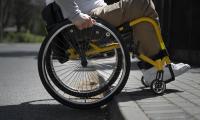 En mand i kørestol forsøger at køre op på fortovet via en høj fortovskant