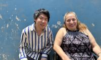 Jacob Nossell og og Fredesvinda fra Honduras sidder foran blå væg og smiler