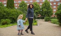 Kvinde og barn med blindestok går tur i park. Kvinden kigger ned på barnet, som hun holder i hånden.