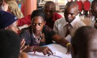 En gruppe unge ugandere er samlet om en flipchart og diskuterer hvad de skal skrive ned