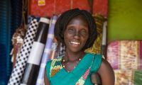 Kvindelig skrædder står foran sin butik i Uganda