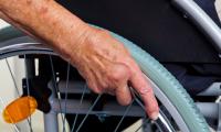 En hånd hviler på hjulet af en kørestol