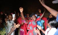 stor gruppe rwandiske kvinder danser, klapper og smiler indendørs