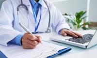 Sundhedstjek: Læge udfylder formular og skriver på computer