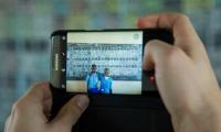 Med en telefon tages et billede af to elever foran en tavle i Rwanda