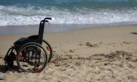 En kørestol står på en strand