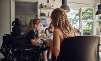 maise på 10 år i kørestol tegner med sine to veninder, der ikke har handicap.