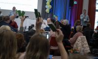 Deltagere rækker hænderne i vejret med stemmesedler